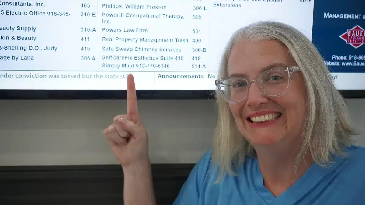 Simply Maid owner Stephanie Ramsey smiling and pointing to the Simply Maid listing on a building directory