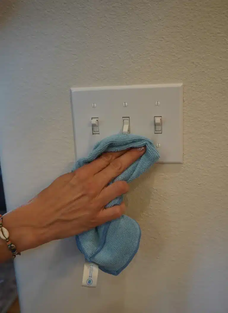 Simply Maid cleaner sanitizing light switches with a microfiber cloth