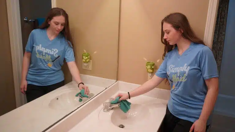 Two Simply Maid cleaners polishing double bathroom sinks