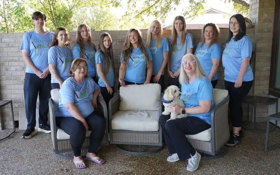 The Simply Maid team in blue shirts with owner Stephanie Ramsey and her dog on a patio, October 2026